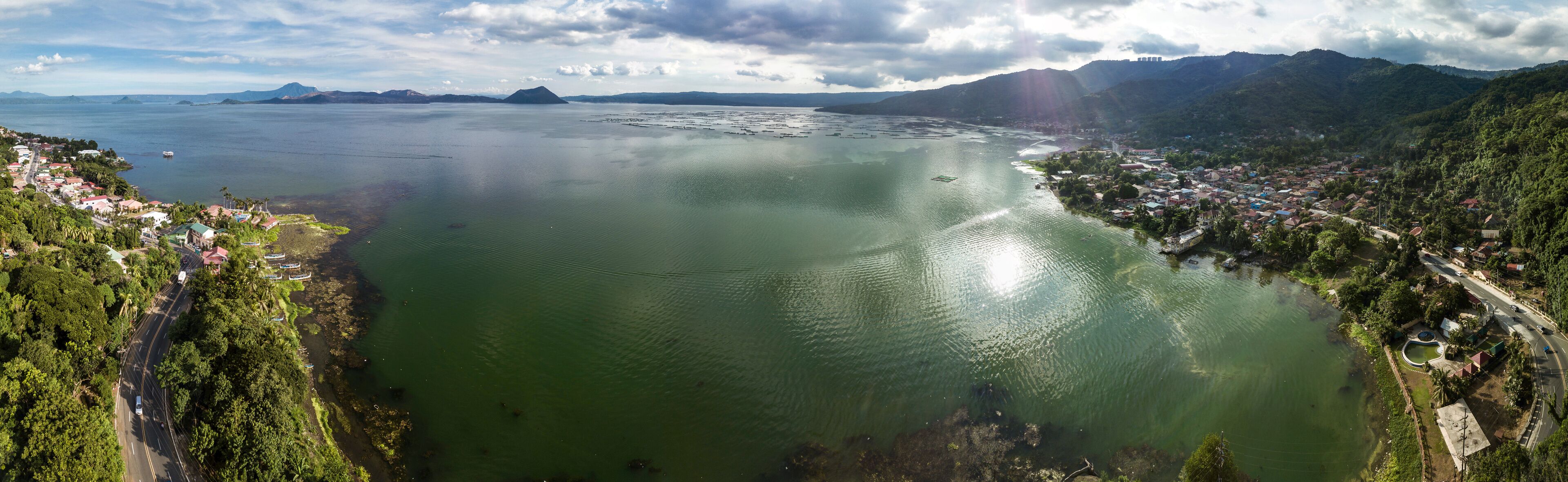 A coastal town with a large body of water, surrounded by mountains and greenery.