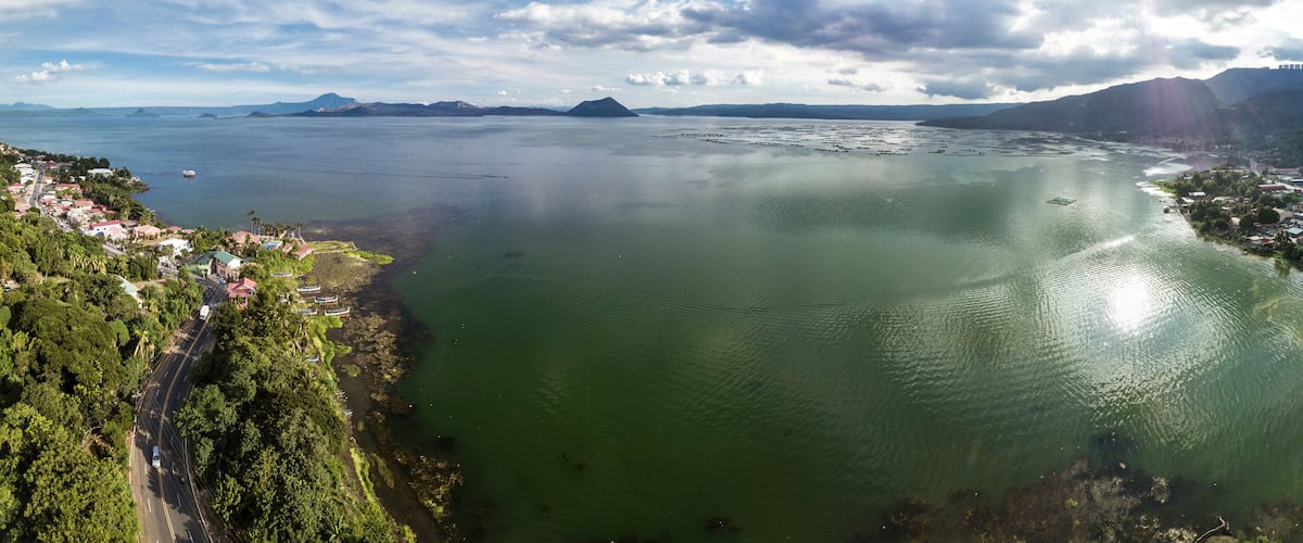 A coastal town with a large body of water, surrounded by mountains and greenery.