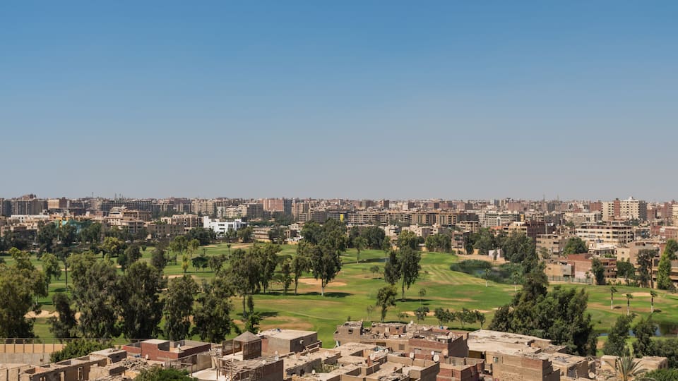 A cityscape with a golf course and residential buildings.