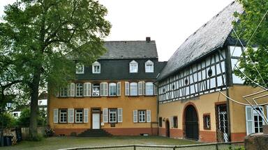 A traditional half-timbered house with a sloped roof and a garden in front.