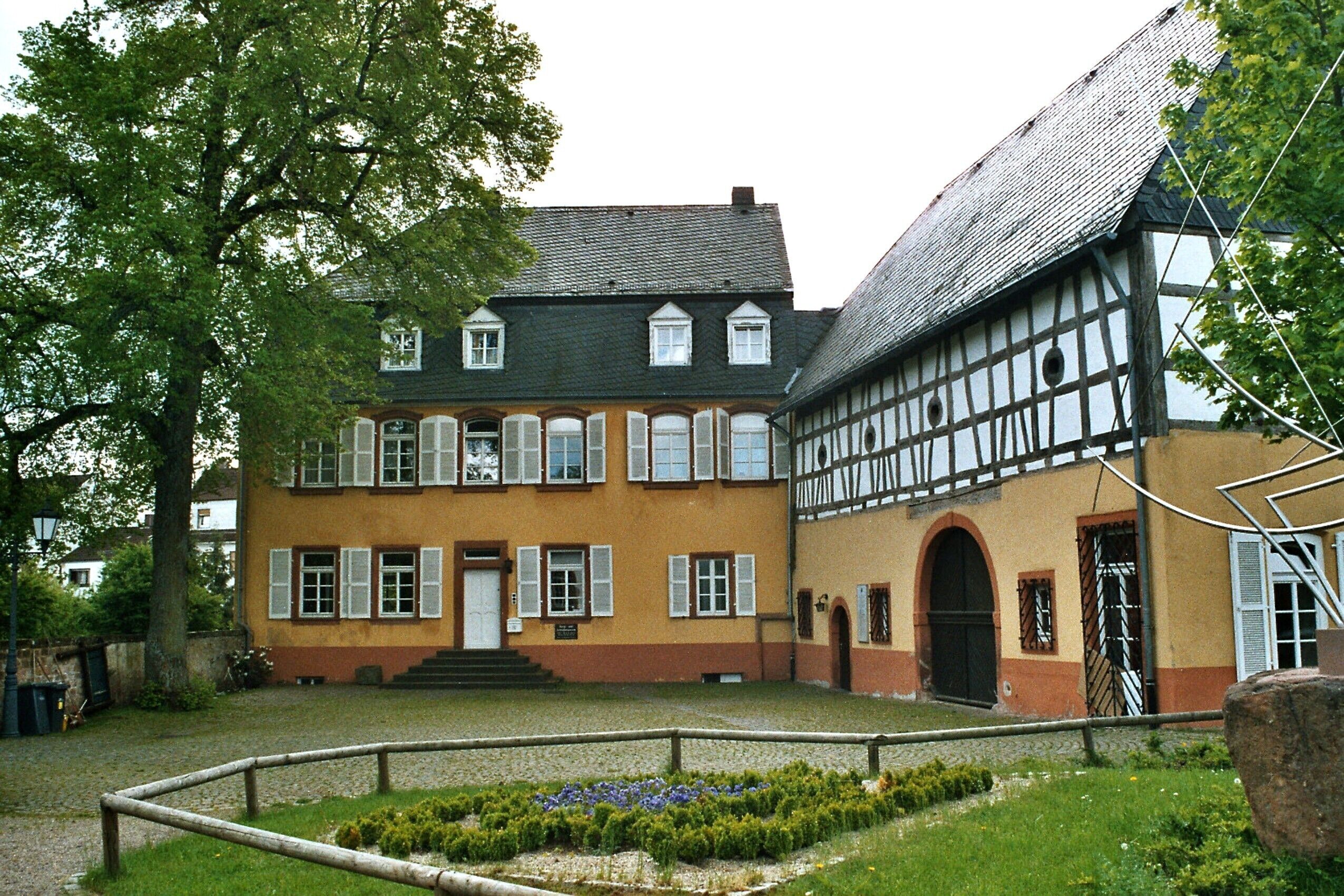 A traditional half-timbered house with a sloped roof and a garden in front.