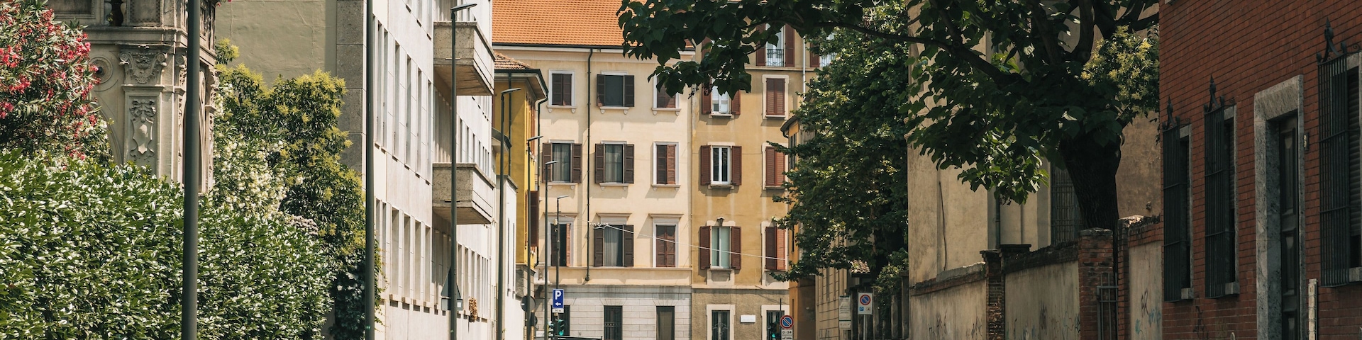Eine Straße mit parkenden Autos, einer Straßenbahnschiene und Gebäuden mit Balkonen.