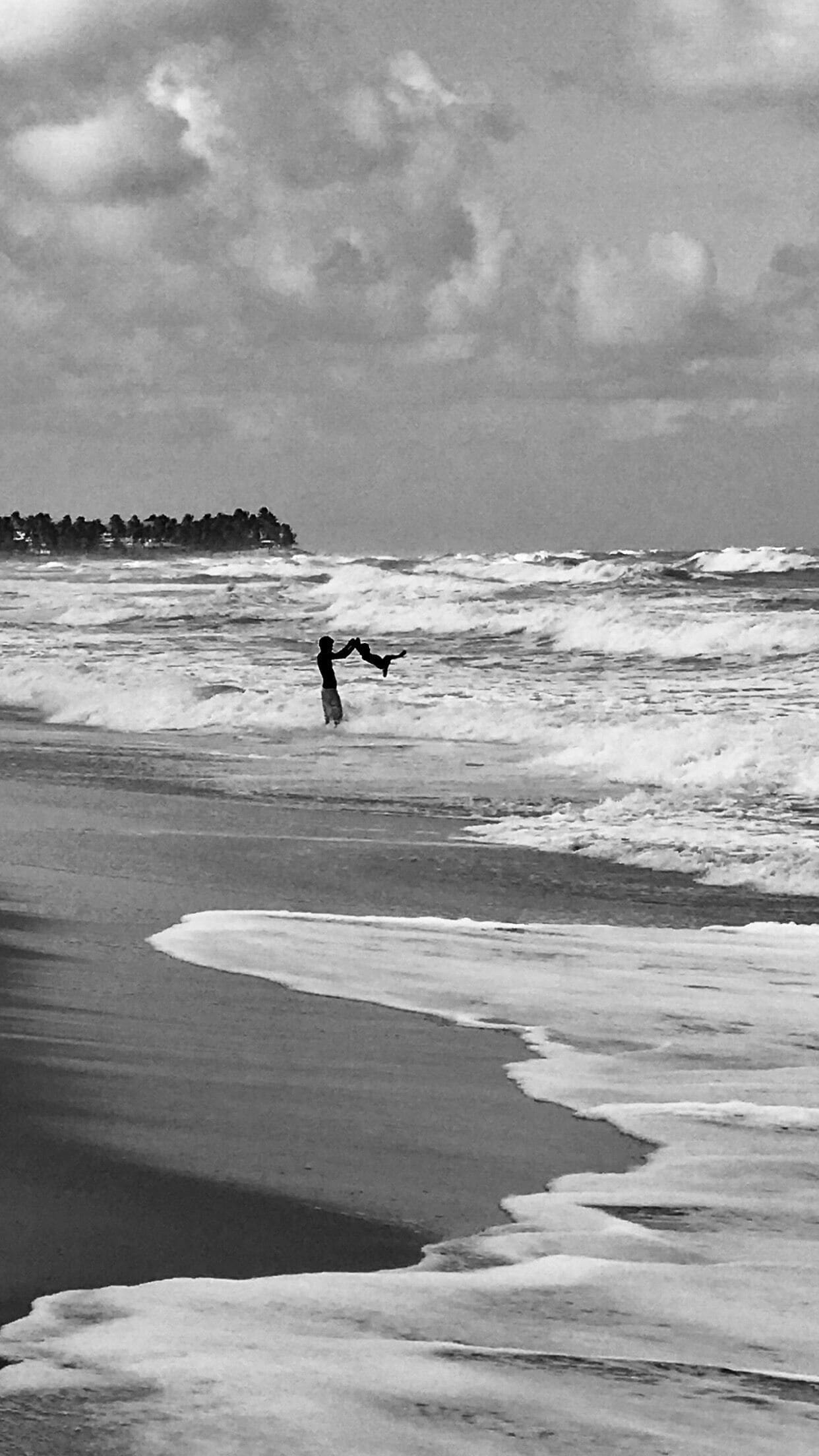 A father playing with his child in the waves. ❤️