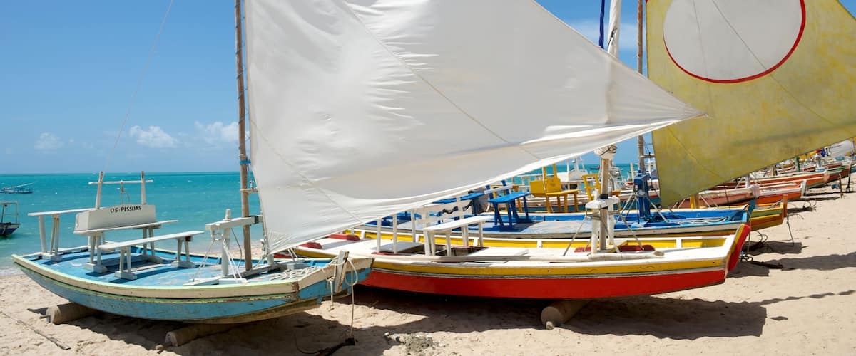 Une plage où plusieurs voiliers traditionnels sont amarrés dans le sable.