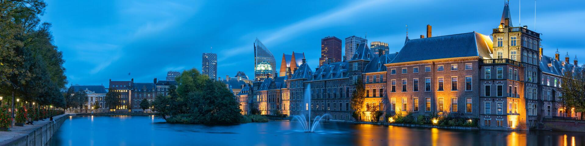 A riverside cityscape with historic buildings and modern skyscrapers.