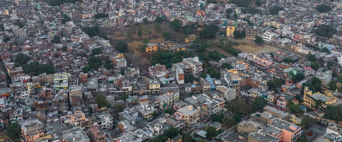 Aerial view of Ganesh Ji Temple surrounded by vibrant buildings and hills, Subhash Nagar, Jaipur, Rajasthan, India.
