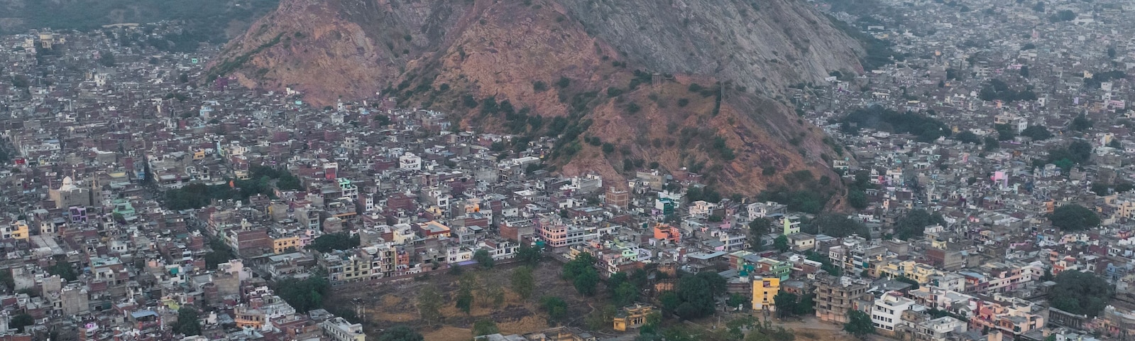 A cityscape with a prominent hill and a fort on top.