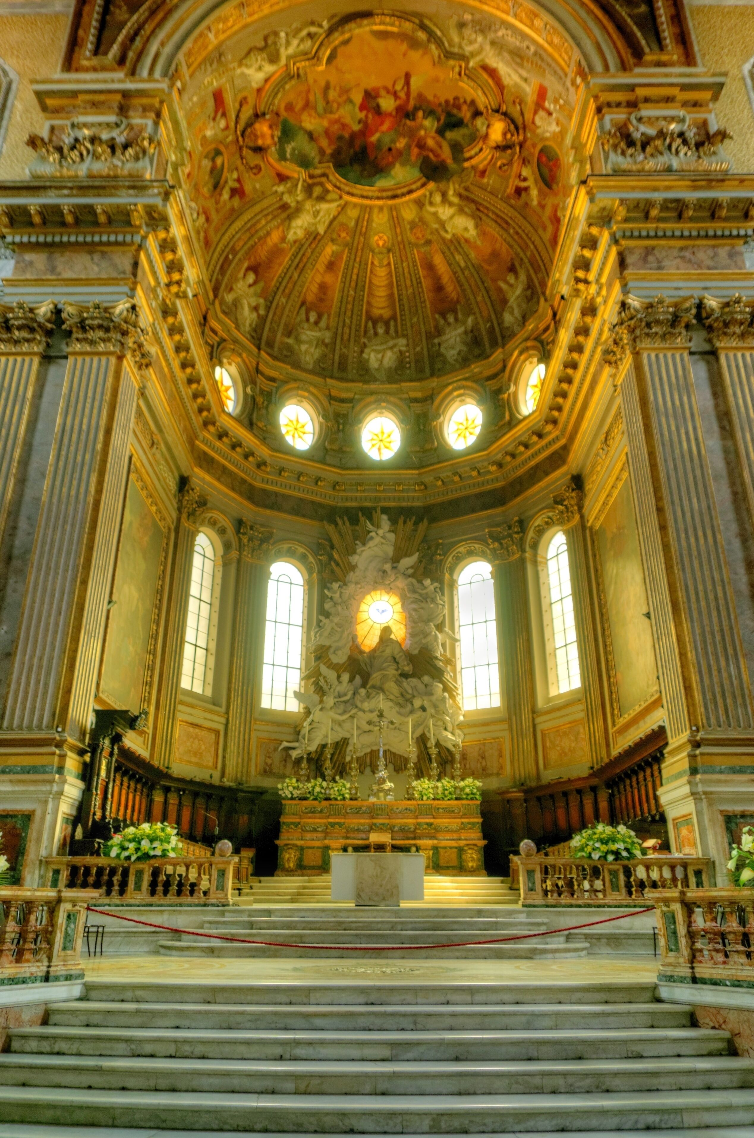 An ornate church interior with a high ceiling, large windows, and a central altar.