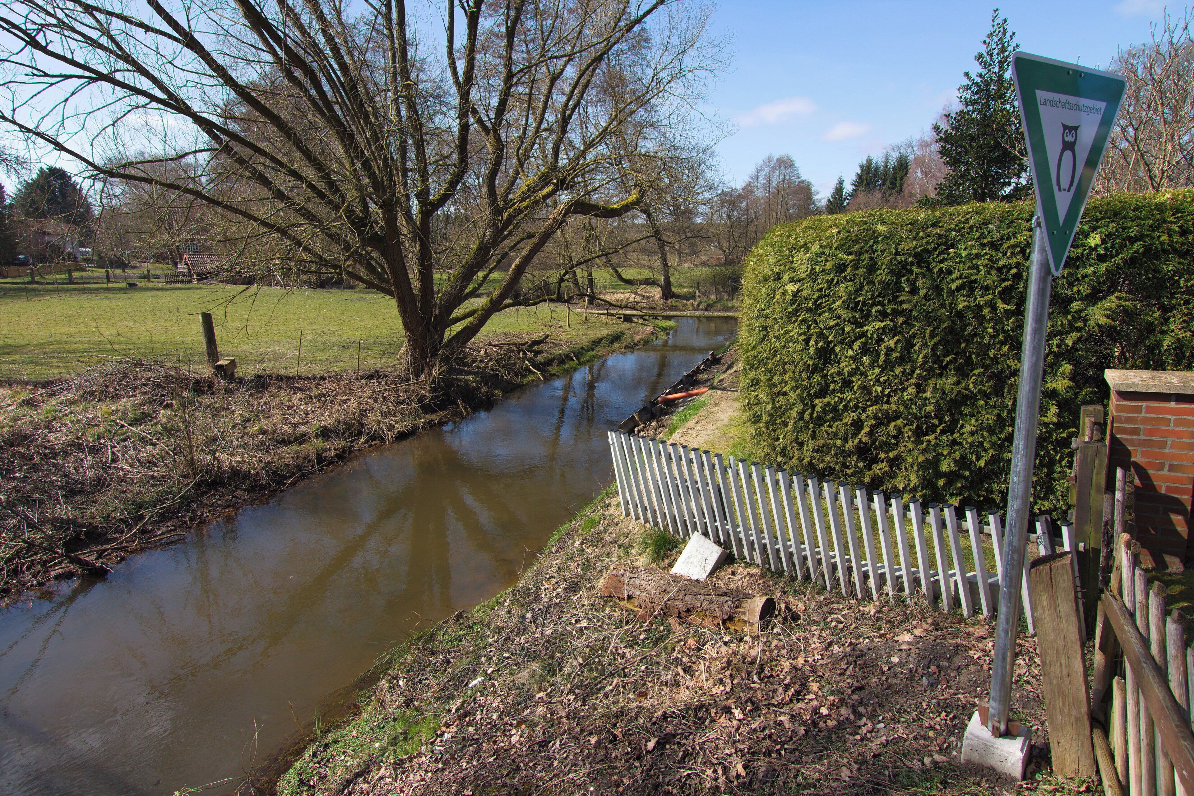 A river flowing through a rural landscape with a sign indicating a wildlife crossing.