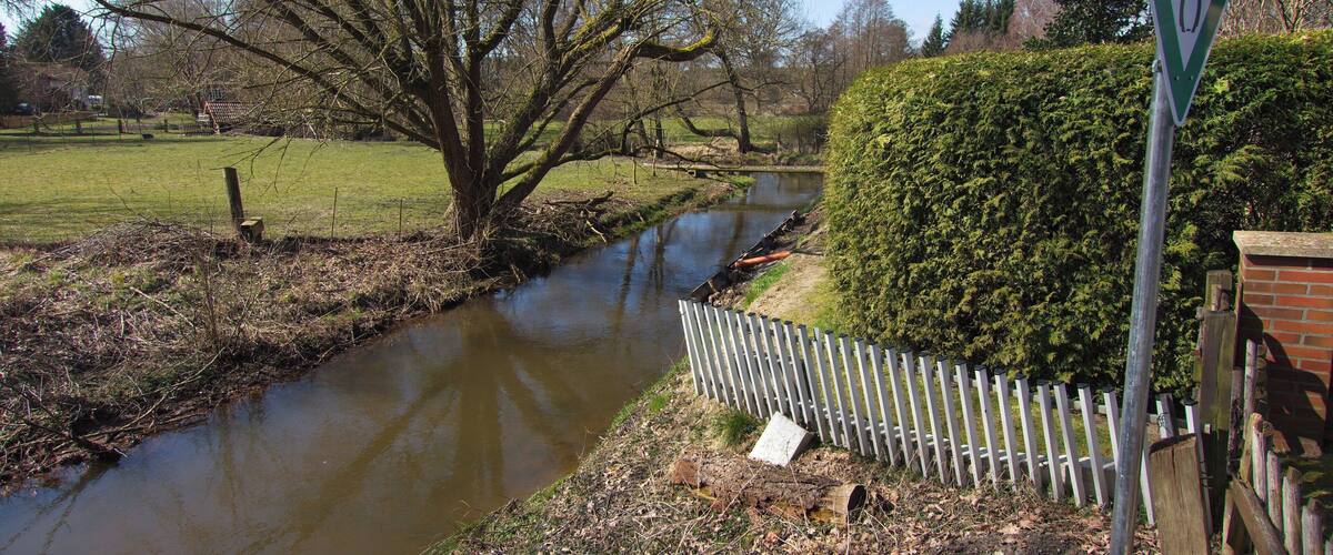 A river flowing through a rural landscape with a sign indicating a wildlife crossing.
