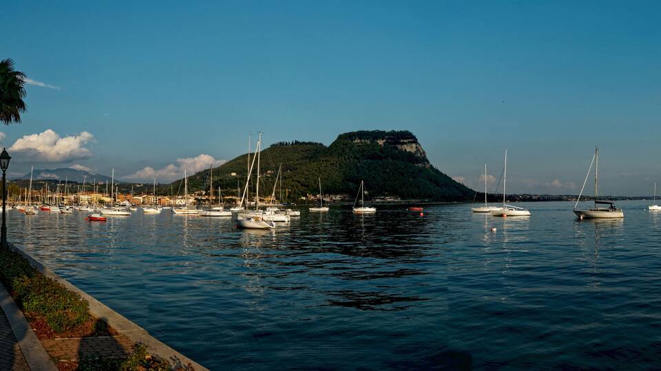 A harbor with boats, a mountain, and a coastal town.