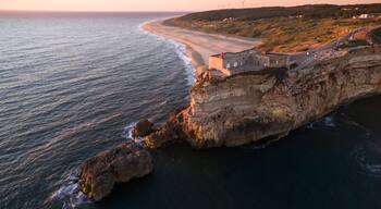 Aerial view of ocean, north Beach and Nazare lighthouse at sunset, Portugal