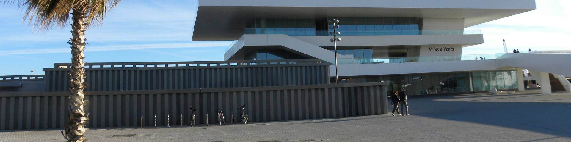 A modern building with a unique architectural design, featuring a palm tree in the foreground.