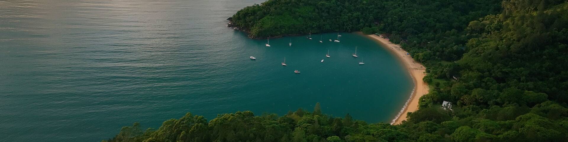 Aerial view of lush tropical archipelago with islands and sailboats at sunrise, Parque Das Palmeiras, Angra dos Reis, Rio de Janeiro, Brazil.