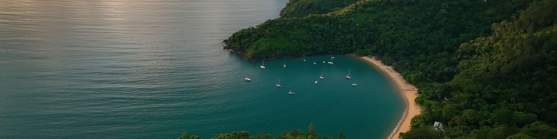 Aerial view of lush tropical archipelago with islands and sailboats at sunrise, Parque Das Palmeiras, Angra dos Reis, Rio de Janeiro, Brazil.