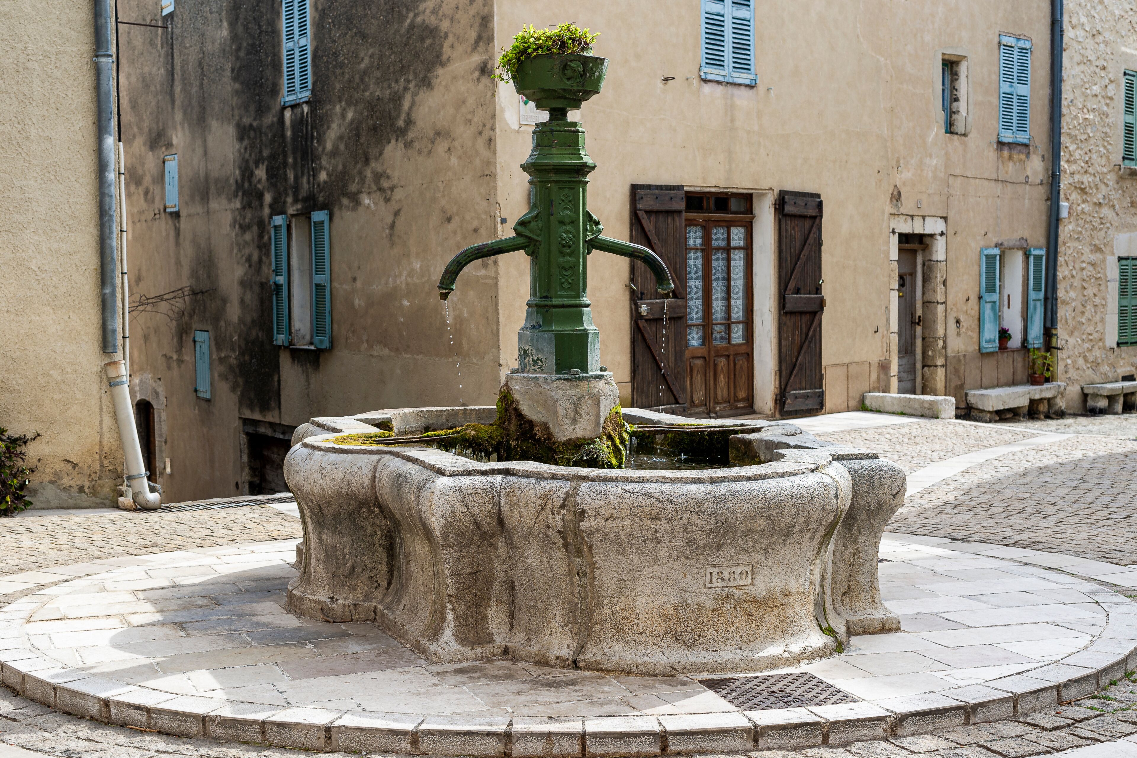 The village of Mons in the country of Calian. Medieval village in the South of France. A square in the center of the village. An old cast iron fountain above a round stone basin.