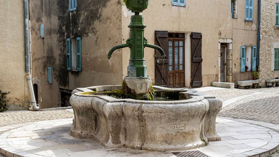 The village of Mons in the country of Calian. Medieval village in the South of France. A square in the center of the village. An old cast iron fountain above a round stone basin.