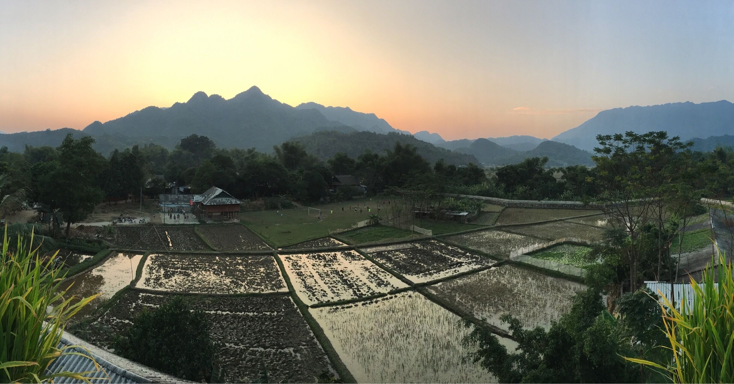 Terraced rice fields, a small building, and mountains in the background.