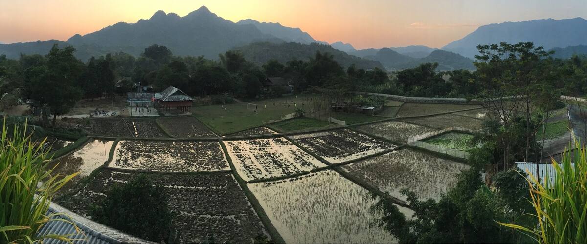 Terraced rice fields, a small building, and mountains in the background.