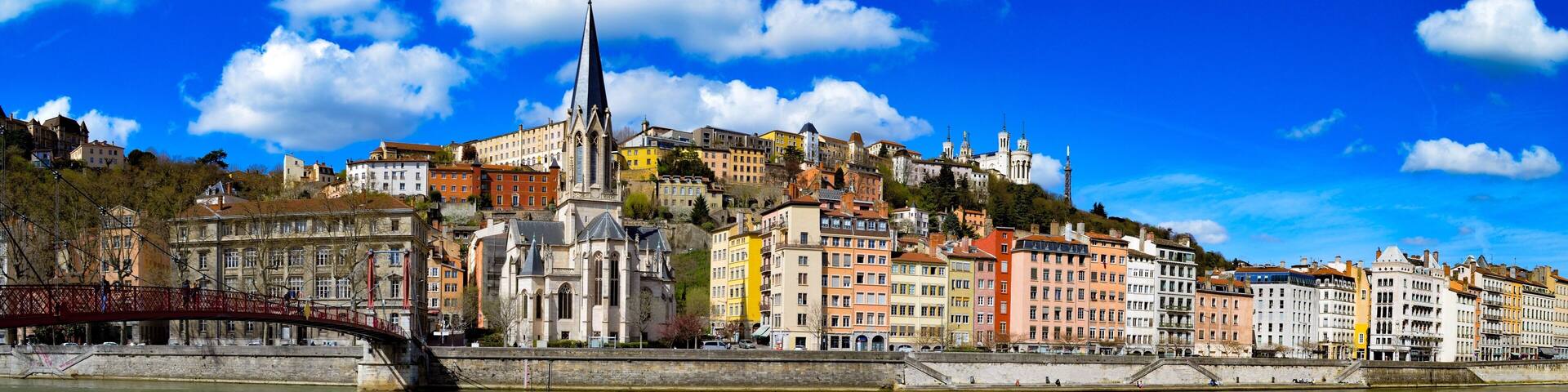 A river with a bridge, colorful buildings, and a church with a tall spire.