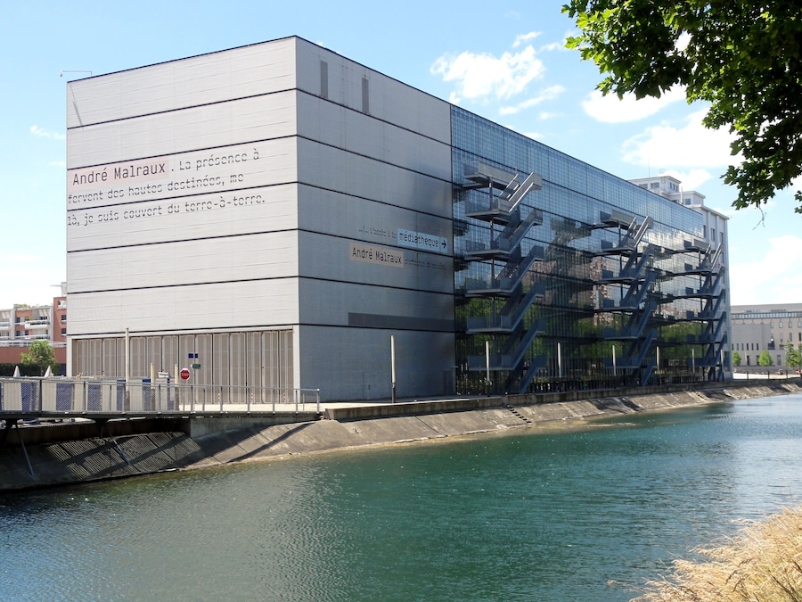 A modern building with a glass facade and a staircase on the side.