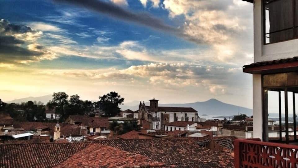 Un pueblo con tejados de terracota, una iglesia destacada y una montaña al fondo.