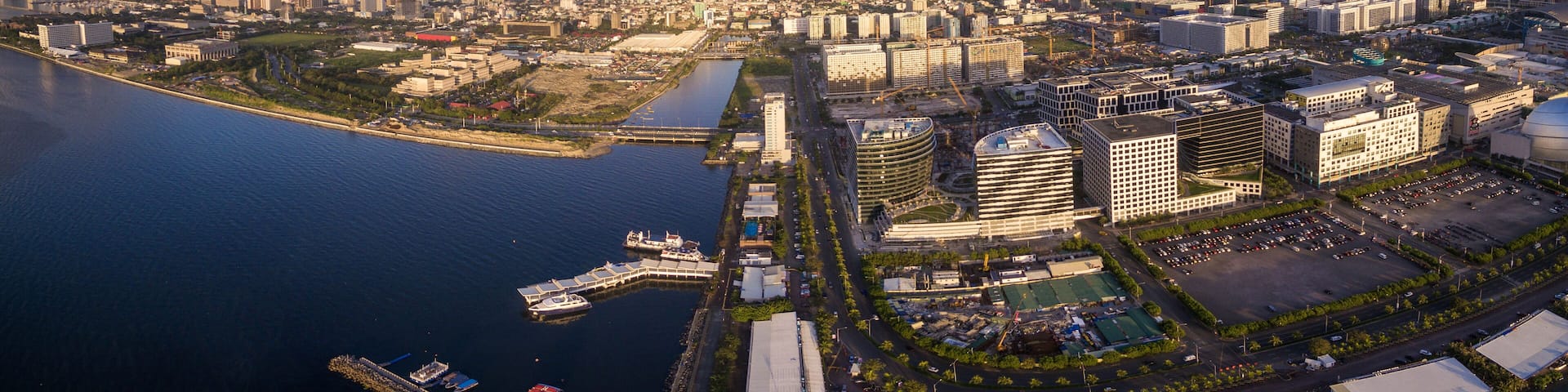 Panorama Photoo of Manila Cityscape in Philippines. Blue Sky and Sunset Light. Pier in Foreground. Business District.