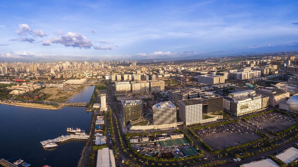 Panorama Photoo of Manila Cityscape in Philippines. Blue Sky and Sunset Light. Pier in Foreground. Business District.