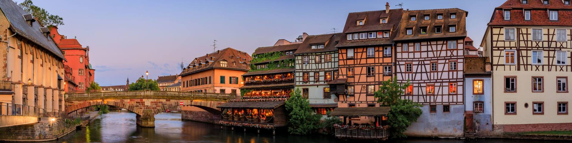 Ornate traditional half timbered houses with blooming flowers along the canals in the Petite France district of Strasbourg, Alsace, France at sunset