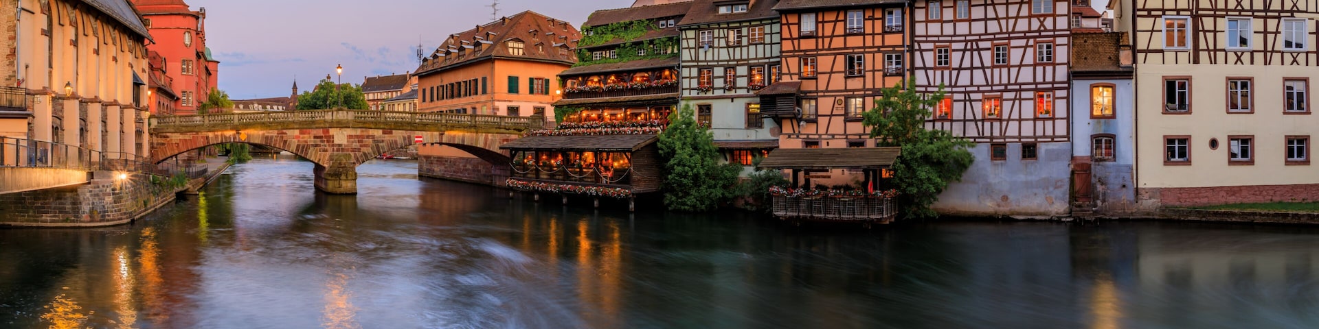Ornate traditional half timbered houses with blooming flowers along the canals in the Petite France district of Strasbourg, Alsace, France at sunset
