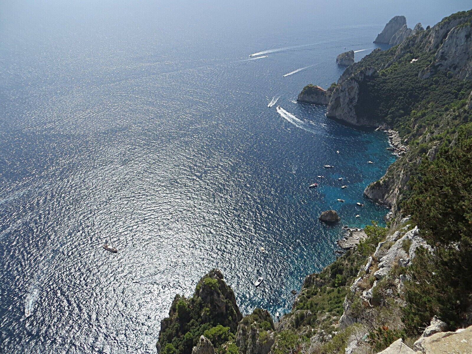 Un paisaje costero con mar azul cristalino, acantilados rocosos y vegetación escasa.