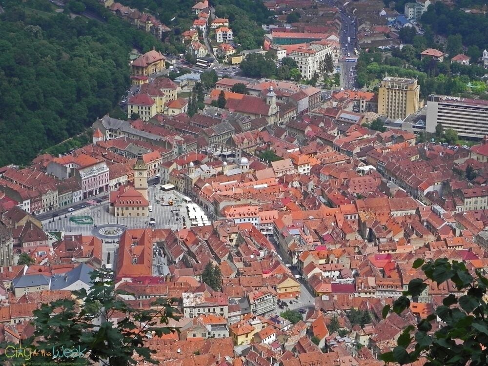 A cityscape with red-roofed buildings, a prominent church, and a hilltop view.