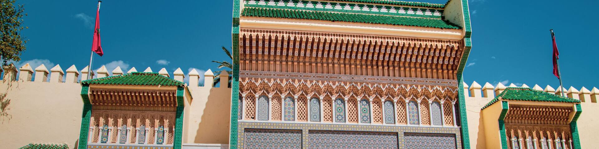 Monumental gate of Fez decorated with zellige tiles, carved arches and golden doors, symbol of traditional Moroccan architecture under a deep blue sky.