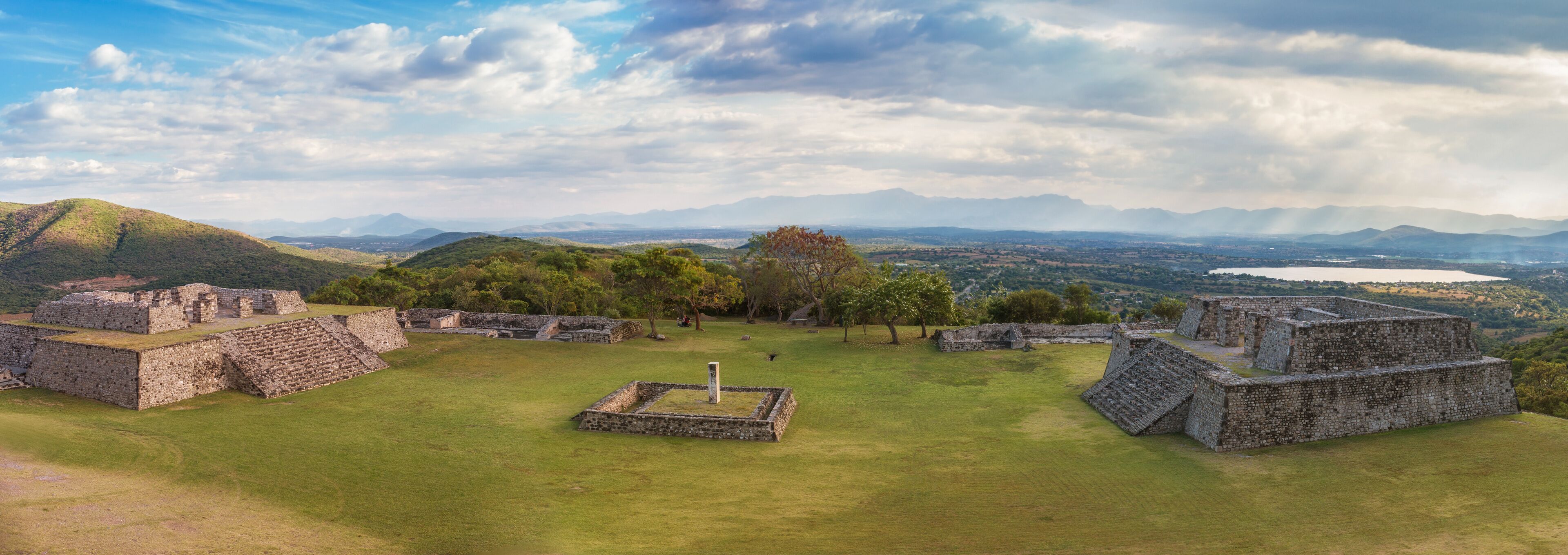 Ancient stone ruins with a grassy field and mountains in the background.