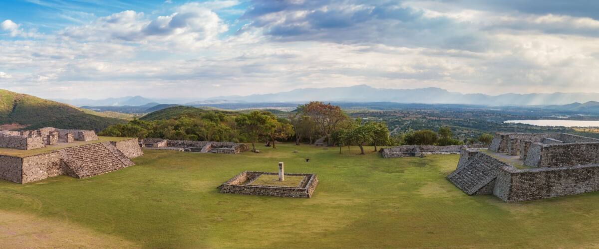 Ancient stone ruins with a grassy field and mountains in the background.