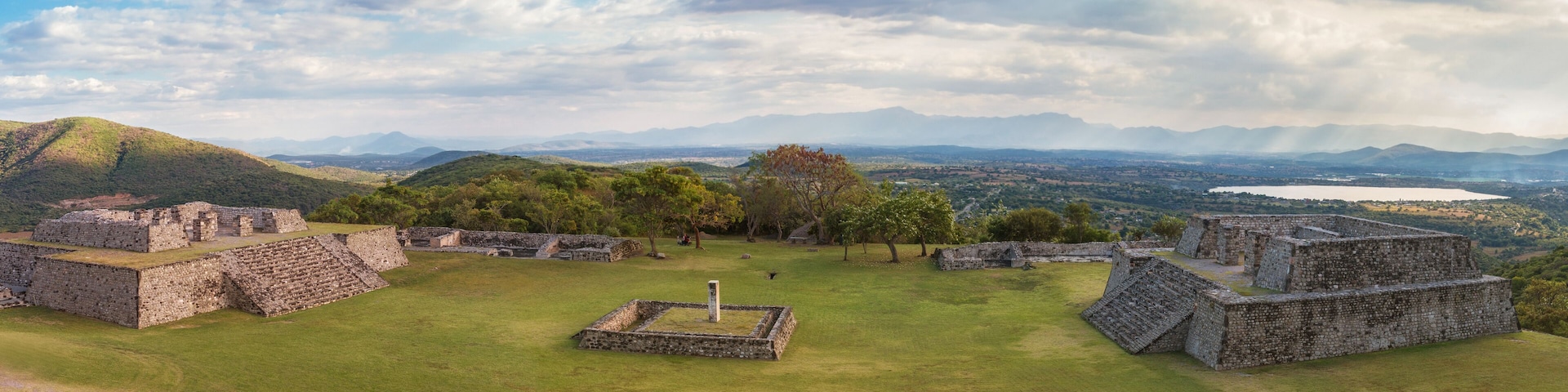Ancient stone ruins with a grassy field and mountains in the background.