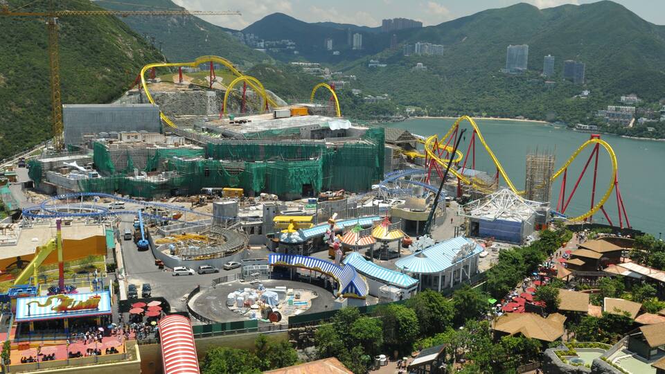 A theme park with roller coasters, a lake, and surrounding hills.