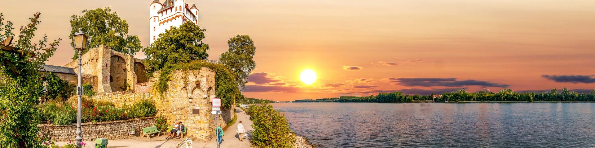 A historic castle by a river at sunset.