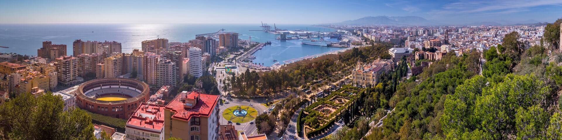 Panoramic view of Malaga city skyline featuring the bullring Mediterranean port and urban architecture in La Malagueta district from a high viewpoint under a clear blue sky in Andalusia Spain.