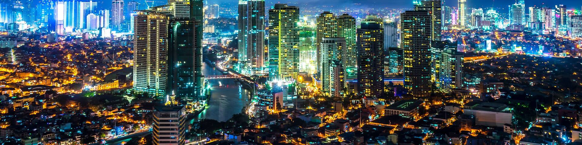 A cityscape at night with illuminated buildings and a large cloud in the sky.