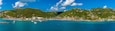 A coastal town with buildings on hills, a marina with boats, and clear blue waters.