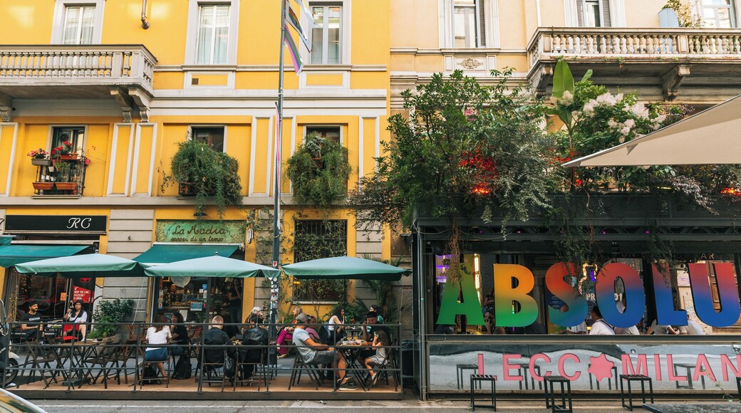 Une rue avec des terrasses, un restaurant appelé « La Radia » et un bâtiment portant l’enseigne « ABSOLU MILAN ».