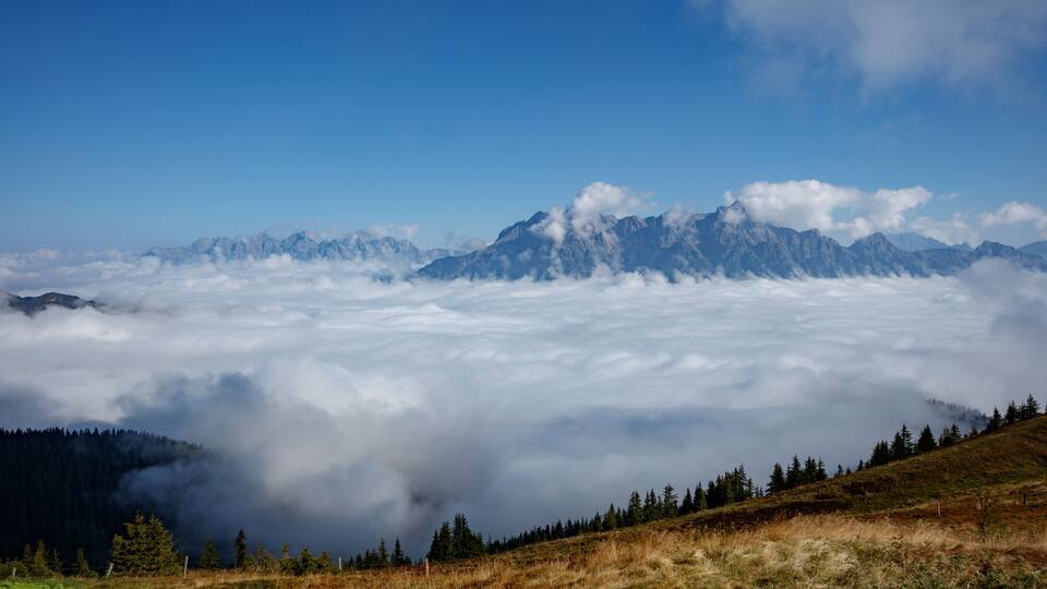 Majestic mountain landscape over cloud blanket in Saalbach Hinterglemm, Austria during clear day