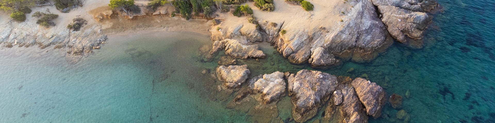 Aerial perspective of the coastal cliffs and lush pine tree park on Grand Gaou Island, overlooking the pristine blue waters of the lagoon. Six-Fours-les-Plages, Provence, French Riviera, France.
