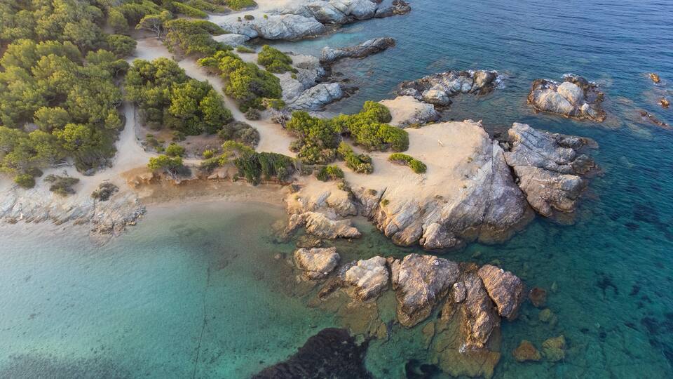 Aerial perspective of the coastal cliffs and lush pine tree park on Grand Gaou Island, overlooking the pristine blue waters of the lagoon. Six-Fours-les-Plages, Provence, French Riviera, France.