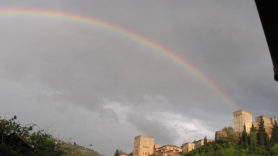 Un castillo en una colina con un arcoíris en el cielo.