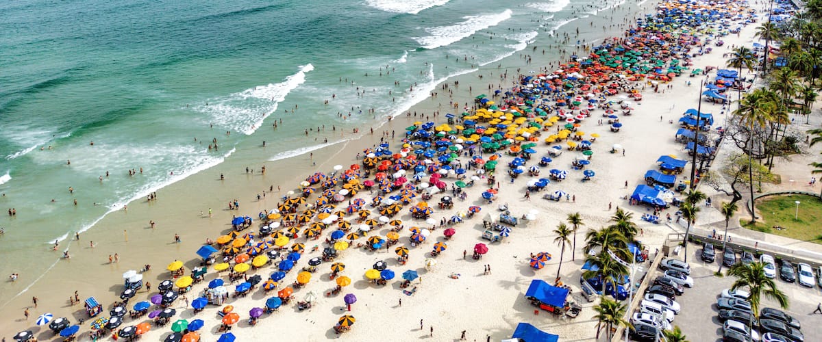 Vista aérea de dia ensolarado com muitos turistas na Praia de Pitangueiras no litoral paulista, Guarujá.