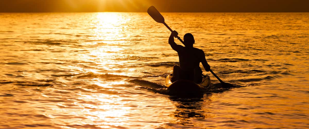 Silhouette of man at sunset paddling in his kayak on the coast of Brazil, Tabatinga beach in São Paulo.