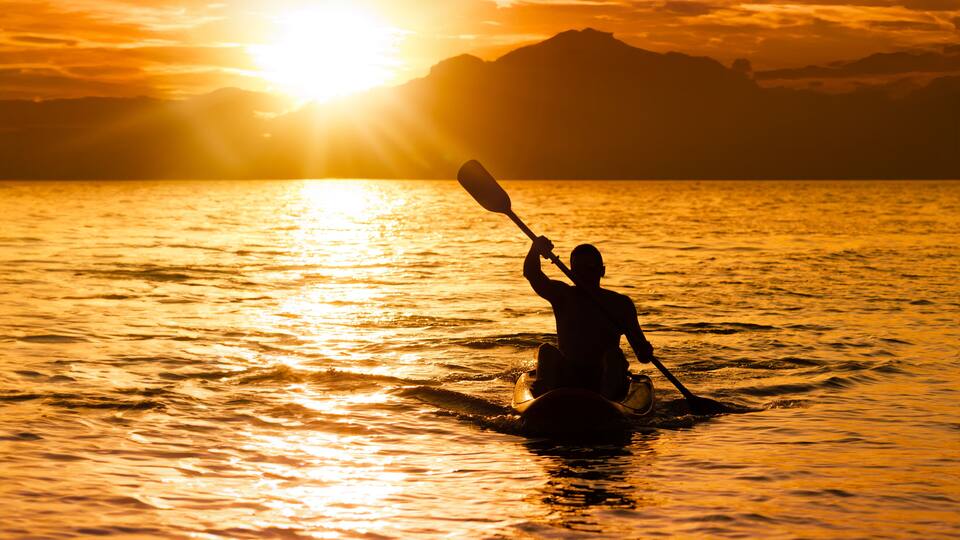 Silhouette of man at sunset paddling in his kayak on the coast of Brazil, Tabatinga beach in São Paulo.