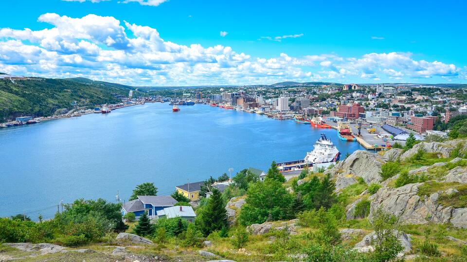 Panoramic views with bight blue summer day sky with puffy clouds over the harbour and city of St. John's Newfoundland, Canada.